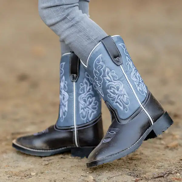 Blue cowboy boots with intricate white patterns on a blurred natural background